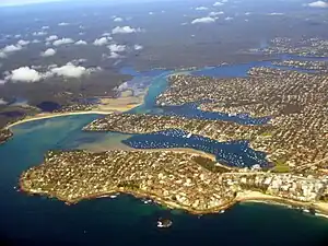 An aerial photograph of an estuary. The land juts into the water like three fingers.