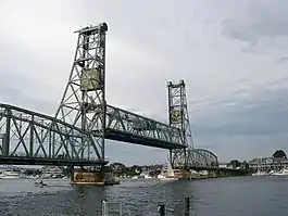 A sailboat passes beneath the open lift span