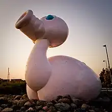 a statue of a pink animal with a duck's lower body and a pig's head