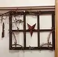 A primitive decoration created using an antique window frame, barn star and pip berry garland