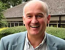 A photograph of Walach smiling in front of a building