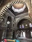 View of the prayer hall of the mosque, with the mihrab on the right; the arches feature ablaq masonry