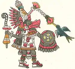 a figure in an Aztec style carrying a round shiled with a symbol similar to a Maltese cross.