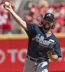 A man in a navy baseball jersey and cap and gray pants