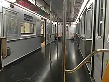 The interior of a R62A subway car used on the 42nd Street Shuttle, which was retrofitted to increase capacity. Almost all of the seats have been removed, original lighting still present.