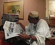 Diab in his living room reading The Citizen with an essay by Magdi Elgizouli and photos by Tobias Zielony for the German Pavilion at the 56th Venice Biennale.