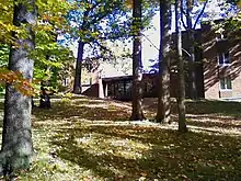 Picture of a building with trees (leaves turning) in the foreground