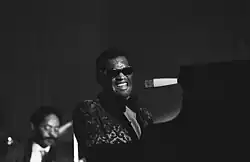 A dark-skinned man wearing dark glasses playing the piano