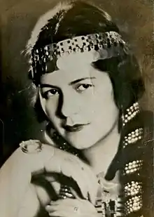 A young woman in a black and white 1930s headshot, with plaited hair interwoven with a metallic headdress