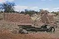 The remains of an adobe barn and an early automobile.