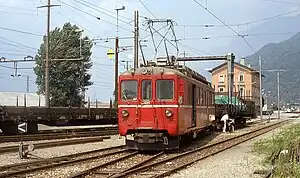 Red locomotive with three-story building in background