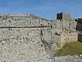 The tower of St. John at the East end of the English sector. The tower was built under Grand Master Antonio Fluvian  (1421–37), and it had a gate. Later a barbican was built around it under Grand Master Piero Raimundo Zacosta (1461–67). Finally the large pentagonal bulwark was built in front of it c. 1487, and the gate was removed.