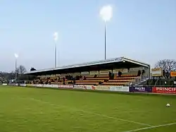 A grandstand at a sports venue. The seats are black and gold.