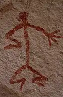 Humanoid stick figure painted on a rock wall in red. The figure is shown in Stylistic group C.