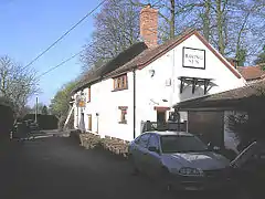 White painted building to the right of the road, with a sign saying The Rising Sun.