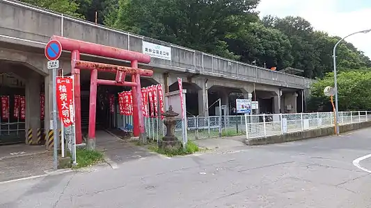 A view of the station entrance and elevated structure. The red torii is not the entrance but leads to a Shinto shrine. The station entrance is to the right of it.