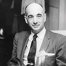 Photo of Robert Lebel standing behind a podium, and speaking at a conference