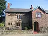 A two-storey stone house with a right protruding wing in brick