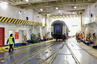 Image showing a railcar on rails inside the white interior of a ferry.