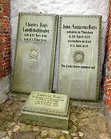 Photograph of three graves; two standing, one small, square one on the ground.