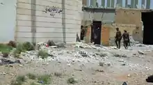 SDF fighters walk through a destroyed area in the suburbs of Raqqa, 13 June 2017