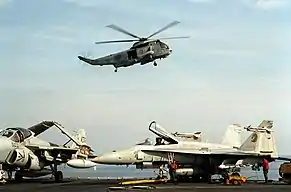 An SH-3H of HS-12 in January 1991 above the USS Midway. Below it to the left is an A-6E TRAM Intruder of VA-115 Eagles and an F/A-18A Hornet of VFA-192 Golden Dragons.