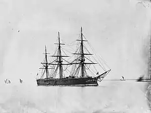 A large black warship with three tall masts