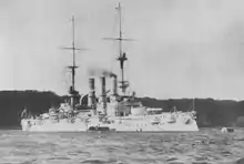 A large warship lies offshore, with a small boat tied alongside.