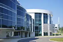 A round white building with dark blue windows, three stories tall.