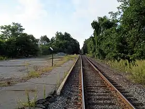 A disused railway platform next to a single active track