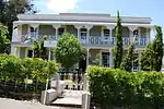 This double-storeyed house was built in 1853 in the Cape Georgian style and victorianised in the late-nineteenth century by the addition of a cast-iron verandah on both levels. The outbuildings, consisting of the original coach house and what is believed.