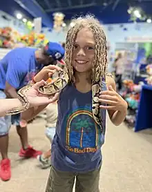 A kid petting a snake at SeaQuest.