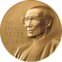 A gold circular medal with a depiction of an elderly man with glasses wearing a jacket buttoned to the neck; the English words "The Shaw Prize" and Chinese characters "邵逸夫獎" engraved on it