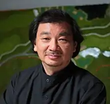 Close-up shot of a man wearing a black shirt, looking directly into the camera.