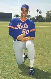 A man in a blue baseball jersey, gray pants, and blue cap