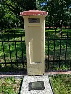 Light-colored stone memorial against a black wrought-iron fence