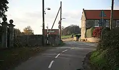 A colour image of a small road junction, with a row of houses