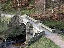 Close up of natural stone arched bridge and tapered piers over the river on a sunny day with blue sky