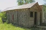 A small two-room frame house next to the commercial building.