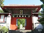 Small wooden gate painted in red, green and blue. Boards with Chinese characters are attached to the gate.