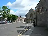 Street scene with houses and pub on the right and trees on the left.