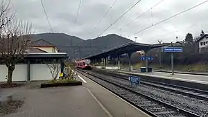 Two-story building with hip roof next to multiple tracks and canopy-covered platforms