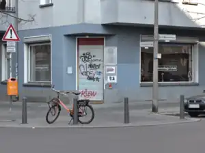 Photograph of a blue corner building with large plate glass windows and a bicycle in front.