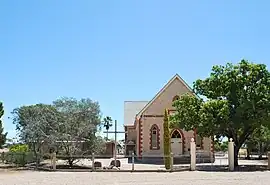 Stone church building with a cross in front