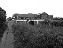 A photograph of a canal with a lock in the foreground. In the background is a large Victorian brick building.