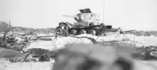 A white, destroyed tank stands on the snow.