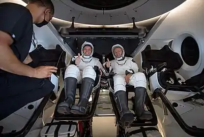 Robert Behnken, left, and Douglas Hurley are seen inside Endeavour onboard GO Navigator being greeted by SpaceX flight surgeon Anil Menon.