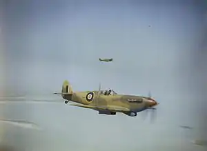 A Spitfire with SAAF markings, flying against a blue sky