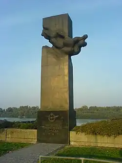 rectangular polished dark stone plinth pointing toward the sky, with a winged plaque and inscription at the base