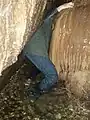 Squeezing past flowstone in the main stream passage